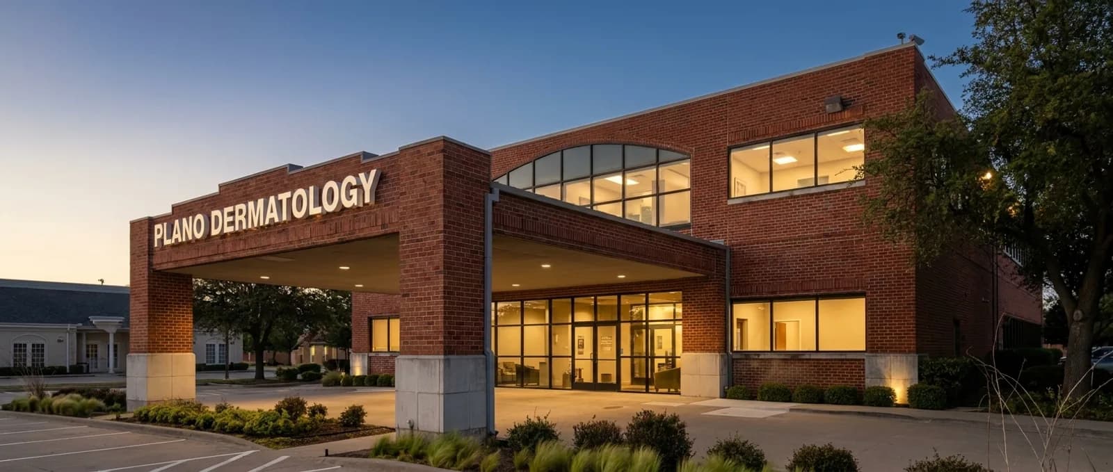 The Plano Dermatology building at dusk, windows glowing